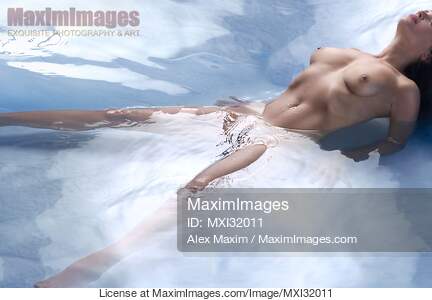 Beautiful nude woman lying in reflective water with her...... preview image