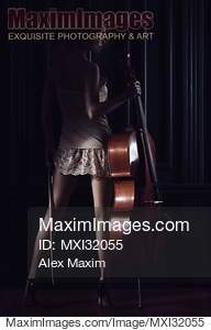 Sexy young woman standing with a cello in dark room with...... preview image