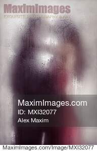 Sensual couple kissing standing behind wet glass in an...... preview image