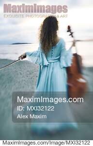 Young woman in a long dress walking towards the ocean shore...... preview image