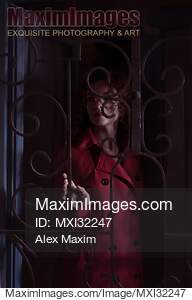Woman standing behind locked grates touching the metal bars...... preview image
