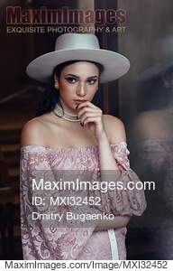 Elegant young woman in pink lace dress and white hat with a...... preview image