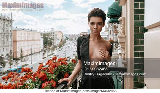 Sexy young woman standing half naked on a balcony covering...... preview image