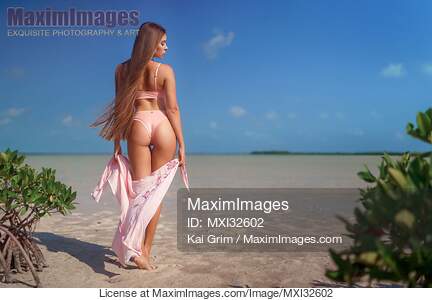 Sexy woman with long hair in pink bikini swimsuit walking...... preview image