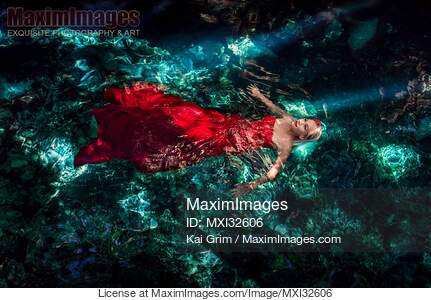 Woman in red flowy dress in clear turquoise water of a...... preview image