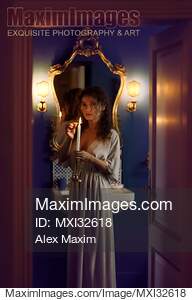 Beautiful woman in evening gown lighting a candle in her...... preview image