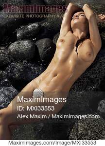 Beautiful nude woman lying on rocks in water with sea shell...... preview image