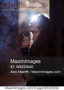 Beautiful woman smoking a cigarette standing on a night city street... preview image