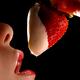 Woman holding strawberry in cream at her mouth... (thumbnail)