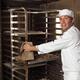 Baker Taking a Rack Trolley out of a Bakery's Oven... (thumbnail)