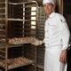 Baker Taking a Rack Trolley out of a Bakery's Oven... (thumbnail)