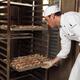Baker Taking a Rack Trolley out of a Bakery's Oven... (thumbnail)