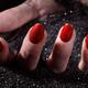 Woman Hand with Red Nail Polish Buried in Black Sand... (thumbnail)