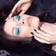 Young woman with blue makeup and manicure lying in water... (thumbnail)