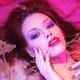 Beauty portrait of woman lying in water with makeup in vivid puple col... (thumbnail)