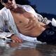 Young man lying on a sea shore in unbottoned wet shirt... (thumbnail)