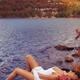 Young woman in white dress lying on lake shore... (thumbnail)