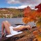 Young woman in white dress lying on shore of lake in fall... (thumbnail)