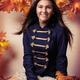 Smiling teenage girl sitting on red autumn leaves
