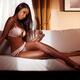 Beautiful young black woman in pink lingerie sitting on sofa... (thumbnail)