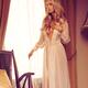Beautiful blond woman in night gown by the window... (thumbnail)