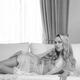 Beautiful young woman with blond hair lying on white sofa Black white... (thumbnail)