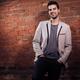 Artistic portrait of a young smiling man standing at brick wall... (thumbnail)