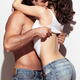 Sensual portrait of a young couple in jeans embracing, man is undressi... (thumbnail)