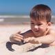 Cute happy little boy playing in the sand on the beach... (thumbnail)