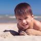 Cute little boy playing in the sand on a beach... (thumbnail)