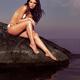 Beautiful Young Woman Wearing Bikini Sitting on Rock... (thumbnail)