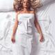 Beautiful woman with long blond hair sleeping on white bed sheets... (thumbnail)