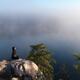 Young woman sitting on rock meditating... (thumbnail)