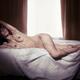 Woman lying naked on a bed by the window... (thumbnail)