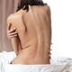 Young woman sitting on bed close up of bare back... (thumbnail)