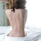 Back of a young woman sitting naked on bed... (thumbnail)