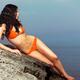 Young woman in red bikini sunbathing by the water... (thumbnail)
