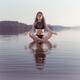 Woman practicing still sitting meditating on platform in the water... (thumbnail)