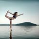 Woman practicing yoga on platform in the water doing Dancer pose... (thumbnail)