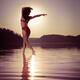 Woman dancing in morning sunlight on water... (thumbnail)