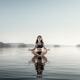 Young woman meditating on platform in the water... (thumbnail)