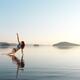 Woman practicing Hatha yoga on a platform in the water Triangle pose... (thumbnail)