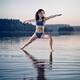 Young woman in blue swimsuit practicing yoga on the water Veerabhadras... (thumbnail)