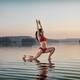 Woman doing Hatha yoga Anjaneyasana Low Lunge pose on the water... (thumbnail)