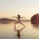 Woman practicing yoga on the water Veerabhadrasana warrior pose... (thumbnail)
