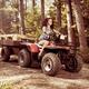 Young farm woman riding atv on country road... (thumbnail)
