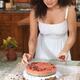 Young woman decorating home-made cake with flowers... (thumbnail)