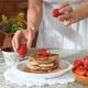 Woman decorating pancakes with strawberries... (thumbnail)