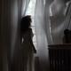 Woman standing at window in dark room... (thumbnail)