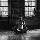 Woman meditating at home in dramatic dim light black and white... (thumbnail)